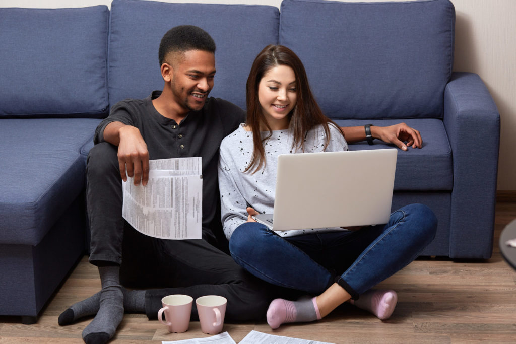 Young couple sitting on floor calculating emergency fund expenses