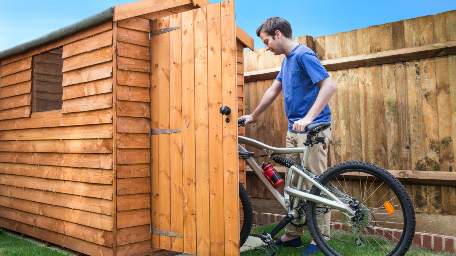 Man pushing his bike into a shed for storage