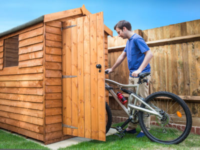 Man pushing his bike into a shed for storage