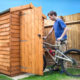 Man pushing his bike into a shed for storage