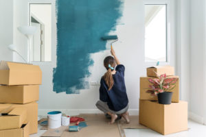 Young woman painting interior wall