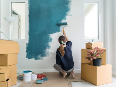 Young woman painting interior wall