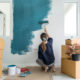 Young woman painting interior wall