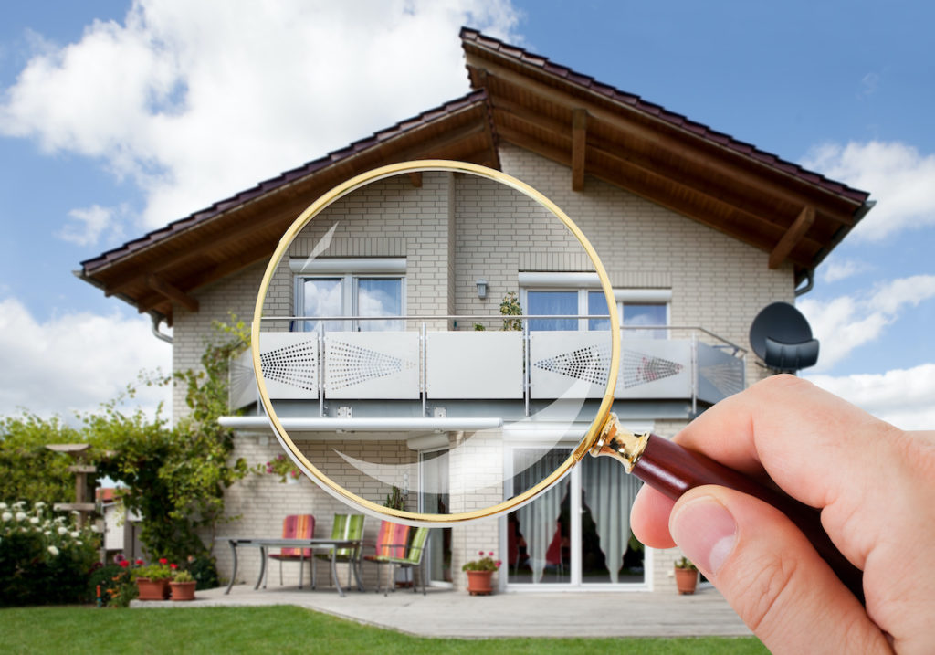 Inspector holds magnifying glass over a home