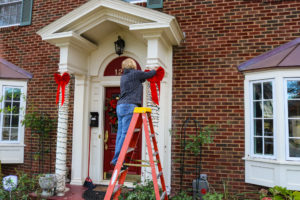Woman on ladder putting Christmas decorations up