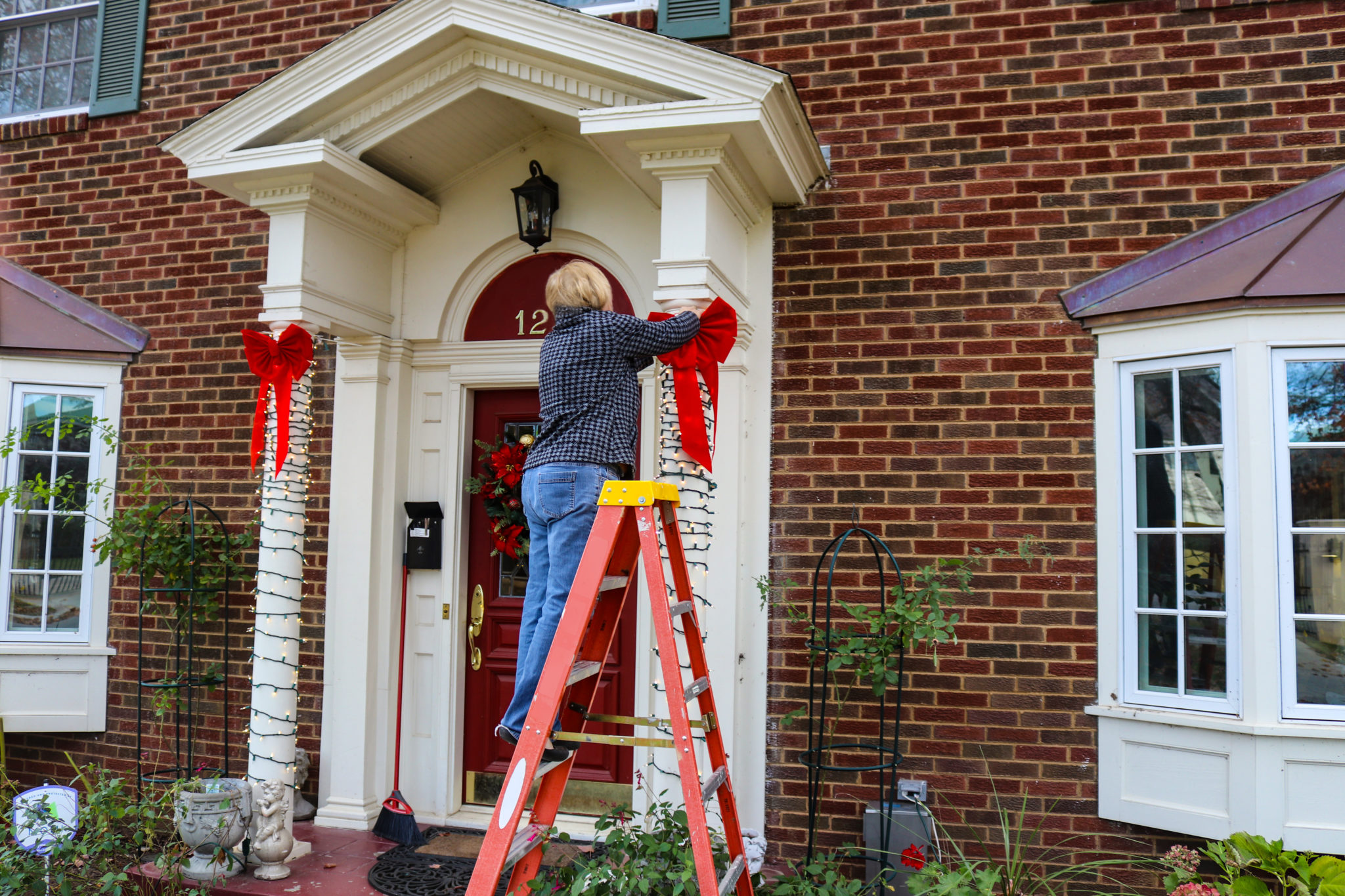Woman on ladder putting Christmas decorations up