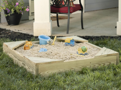 Sandbox with toys in a back yard.