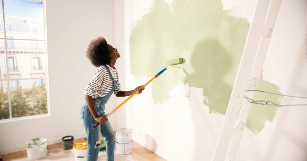 Young woman painting wall with roller