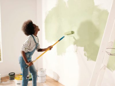 Young woman painting wall with roller
