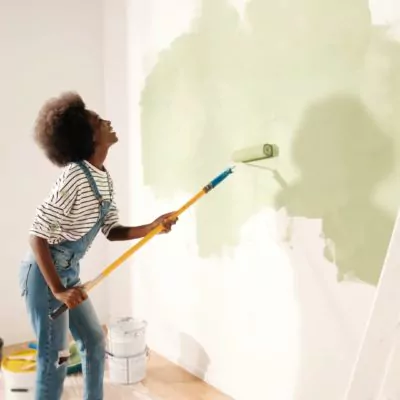 Young woman painting wall with roller