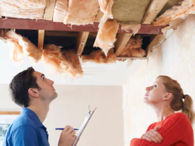 Builder And Client Inspecting Roof Damage