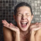 Young woman reacting in shock to hot or cold shower water