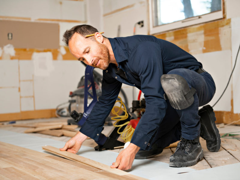 Professional flooring contractor installing a new wood floor in a house.