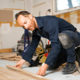 Professional flooring contractor installing a new wood floor in a house.