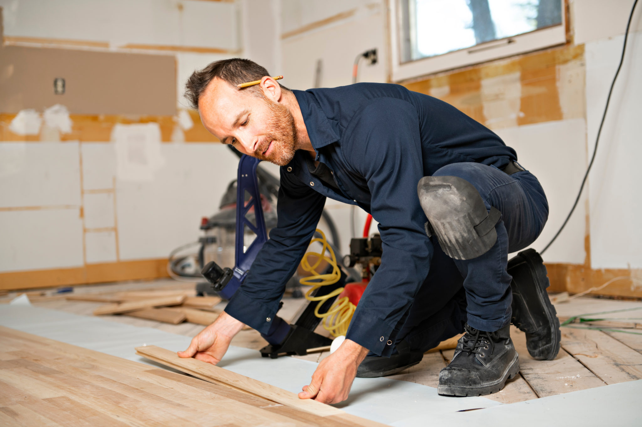 Professional flooring contractor installing a new wood floor in a house.