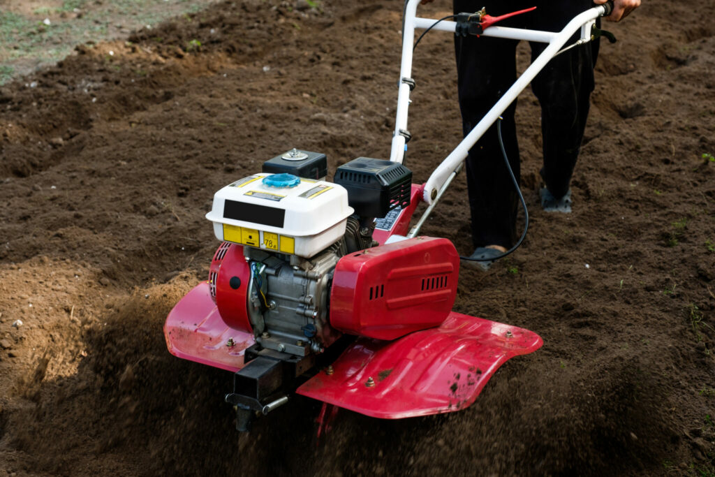 Man working in the garden with garden tiller 