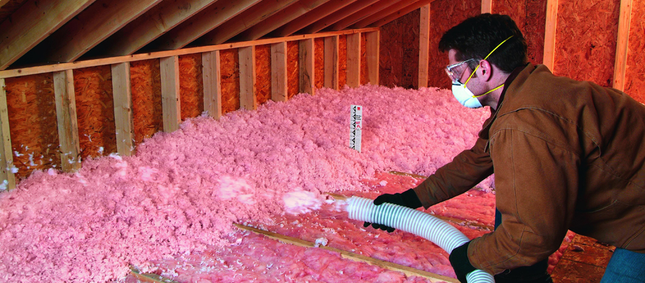Man adding blowin in insulation to an attic