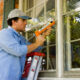 Man on ladder caulking outside window