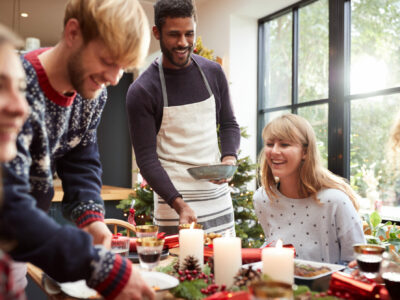Group Of Friends Sitting Around Dining Table At Home As Christmas