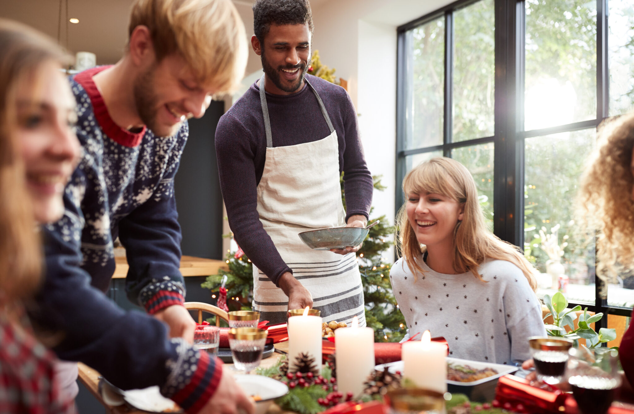 Group Of Friends Sitting Around Dining Table At Home As Christmas