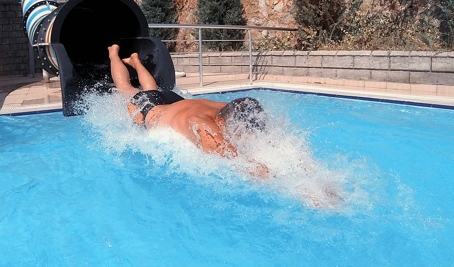Man exiting a water slide built into a pool