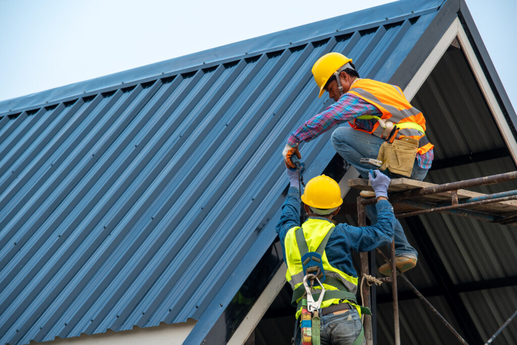 Roofer using air or pneumatic nail gun and installing metal roof